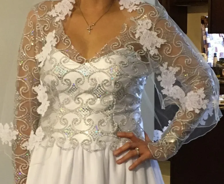 Close-up of silver scroll beadwork and white lace appliqués on sheer illusion sleeves